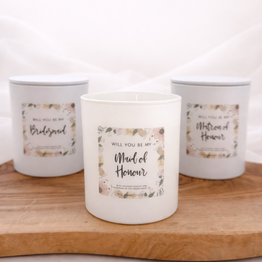 Three candles with labels on a wooden board against a white background