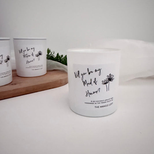 White candles with text and floral designs on a white surface